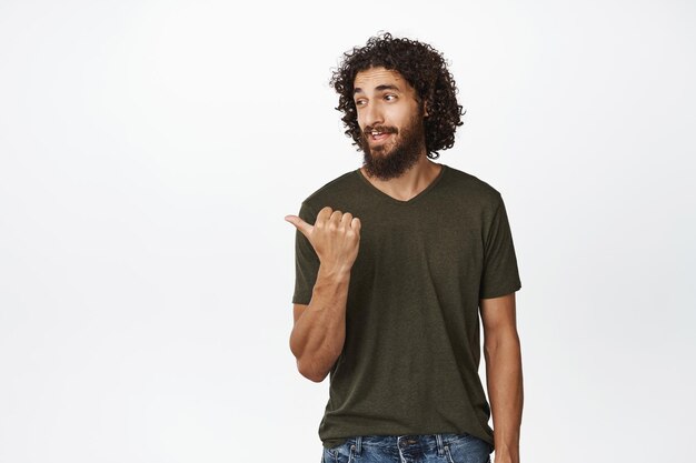 Красивый средний пасхальный бородатый мужчина, указывающий и смотрящий влево нахальное выражение лица, показывающий баннерную рекламу веб-сайта на копировальном пространстве на белом фоне