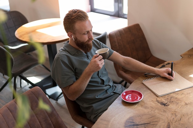 一杯のコーヒーを保持しているハンサムな現代人