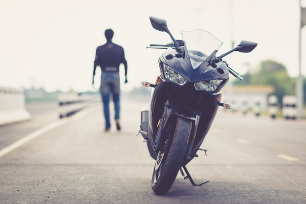 Красивый мотоциклист с шлемом в руках мотоцикла