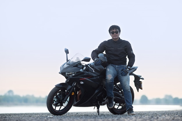 Handsome motorbiker with helmet in hands of motorcycle