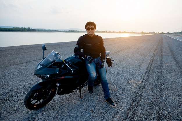 Bello motociclista con il casco nelle mani della moto