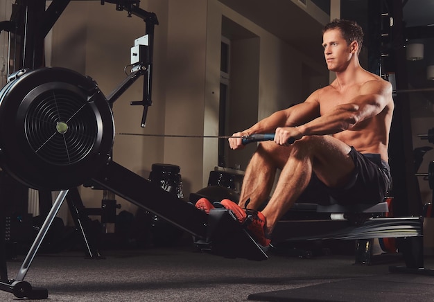 A handsome muscular fitness male doing exercise on the rowing machine.