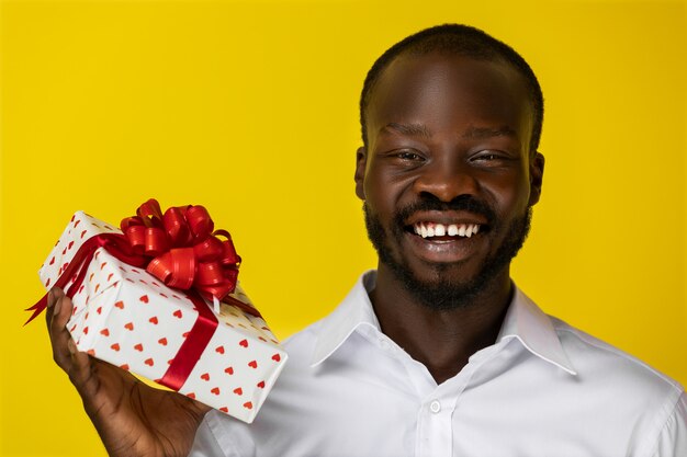 Handsome Negro smilling at camera and holding a gift box