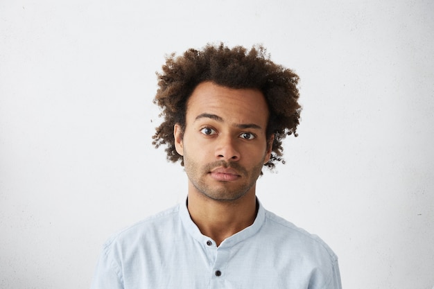 Handsome office worker wearing blue shirt posing in studio raising one brow