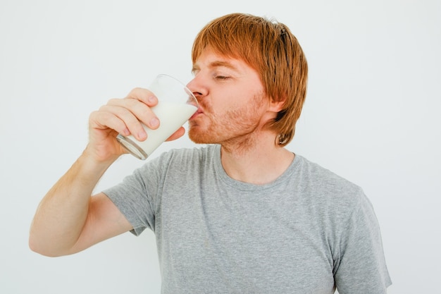 ガラスからミルクを飲むハンサムな赤毛の男