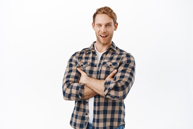 Handsome redhead man wink at you encourage to try something cross arms on chest standing in confident professional pose concept of repairment works and services