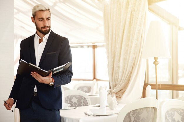 Handsome restaurant manager is controlling the work process