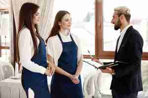 Free photo handsome restaurant manager is talking to waitresses about work process