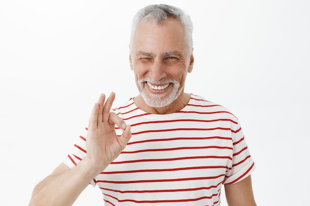 Foto gratuita bell'uomo anziano impertinente assicura, mostrando il gesto giusto e sorridendo soddisfatto