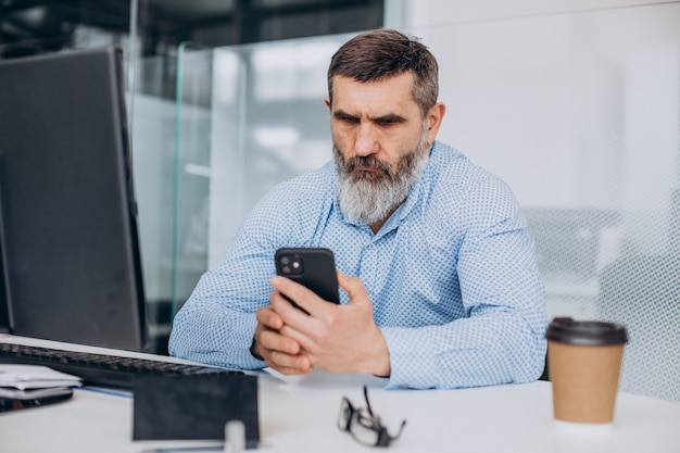 Foto gratuita uomo d'affari anziano bello che lavora al computer in ufficio