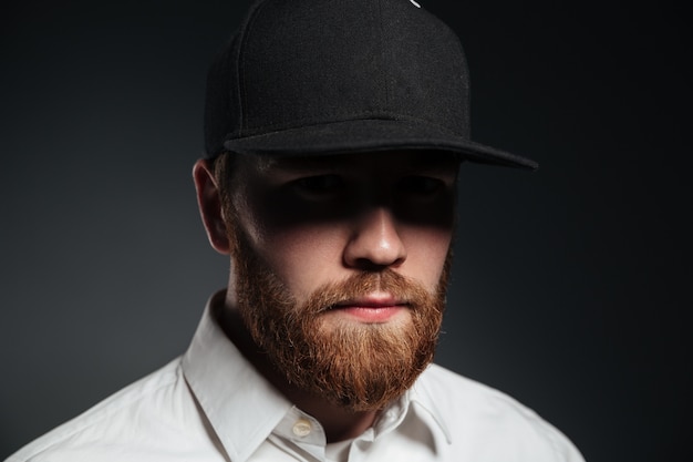 Free photo handsome serious bearded young man wearing cap