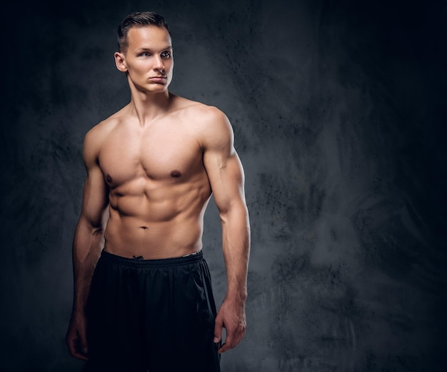 Handsome shirtless athletic male over grey vignette background.