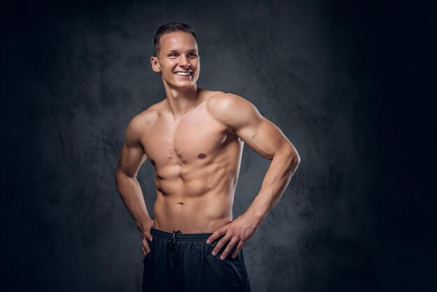 Handsome shirtless athletic male over grey vignette background.