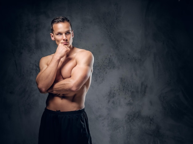 Handsome shirtless athletic male over grey vignette background.