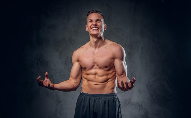 Handsome shirtless athletic male over grey vignette background.