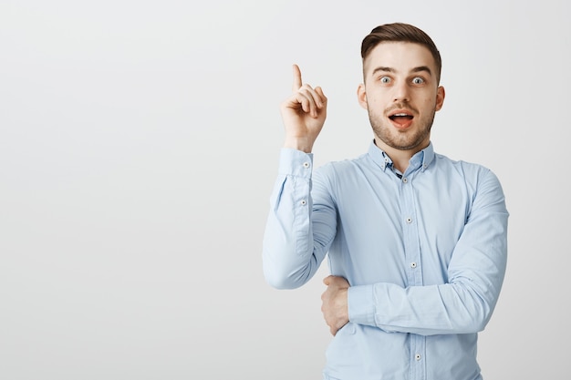 Handsome smart guy found solution, raising index finger in eureka gesture