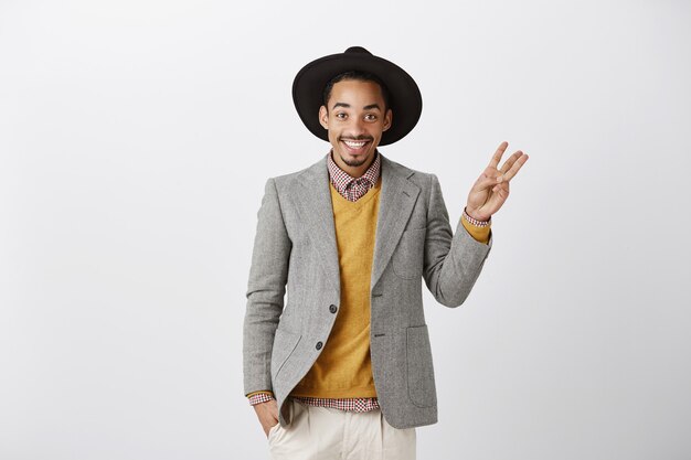 Handsome smiling african-american man in stylish suit showing number three, making order