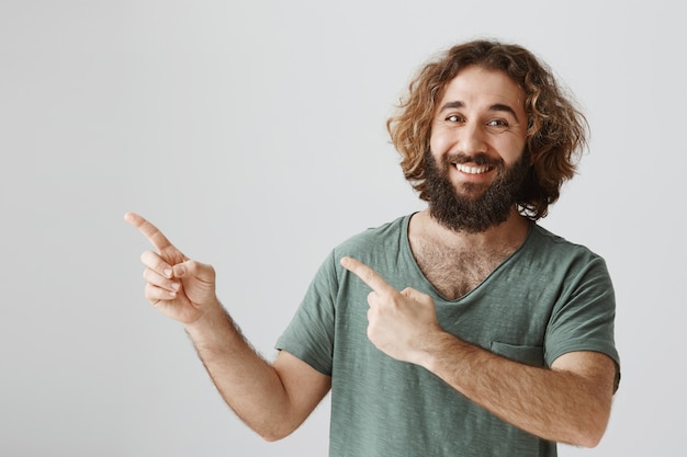 Handsome smiling bearded arabic guy pointing upper left corner, make announcement