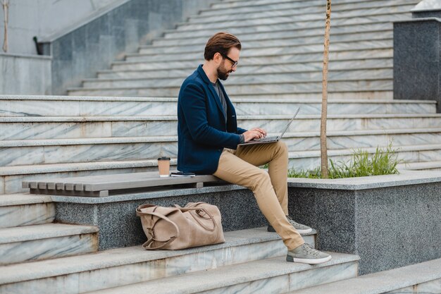 Handsome smiling bearded man in glasses working on laptop