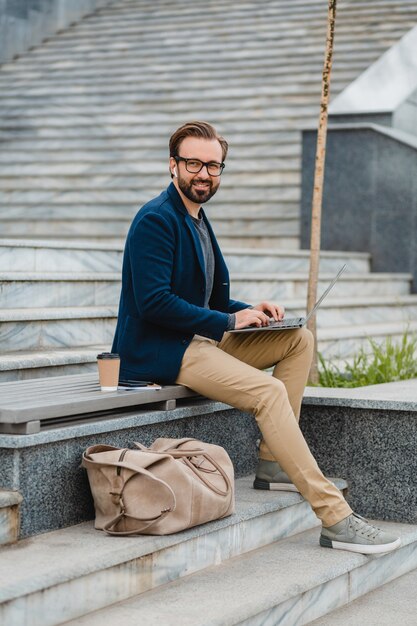 Handsome smiling bearded man in glasses working on laptop