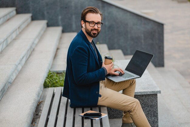 Красивый улыбающийся бородатый мужчина в очках, работающих на ноутбуке