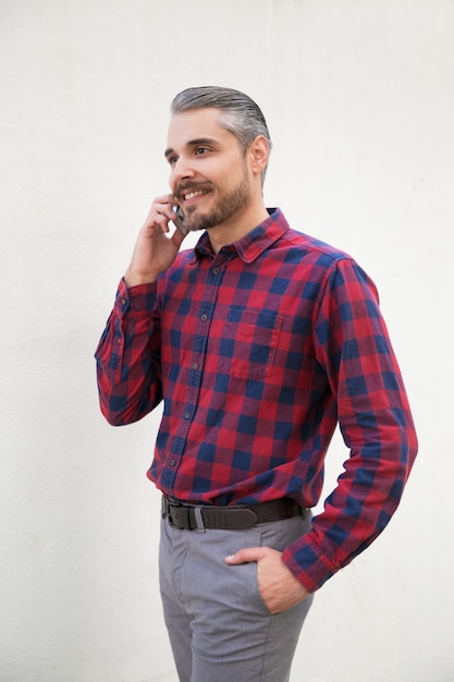 Handsome smiling bearded man talking by smartphone