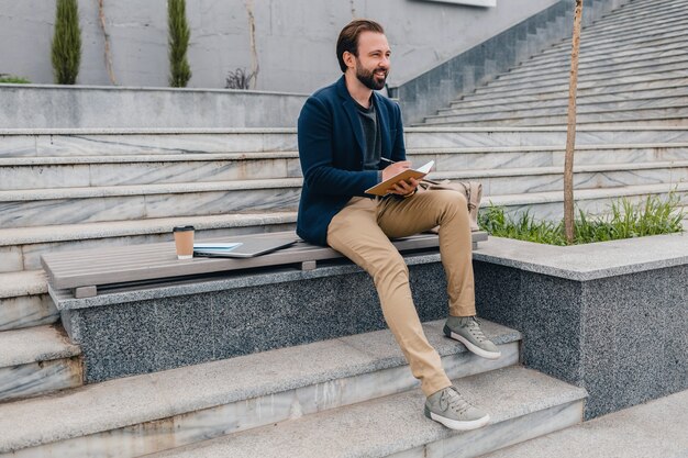 Handsome smiling bearded man working, writing in note book