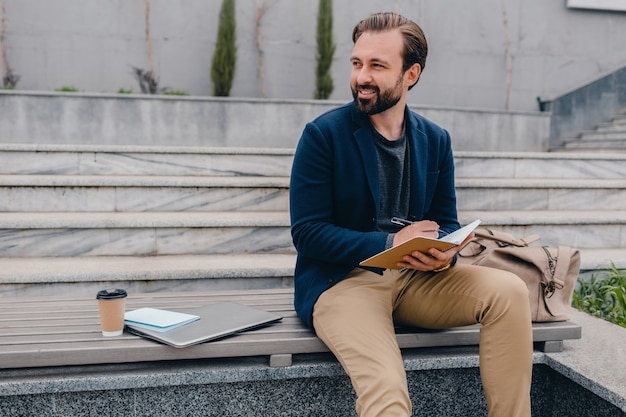 Handsome smiling bearded man working, writing in note book