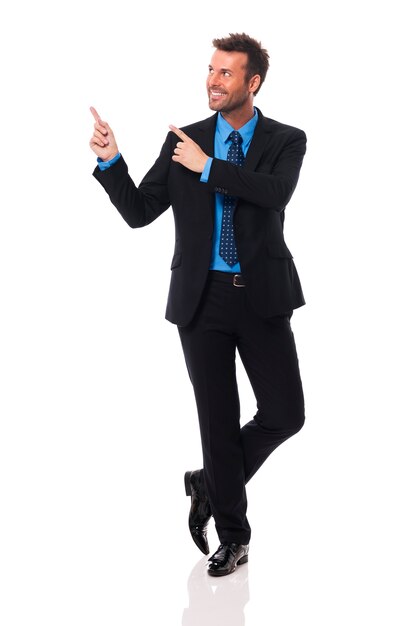 Handsome and smiling businessman pointing at copy space  
