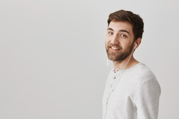 Handsome smiling guy listening music in headphones