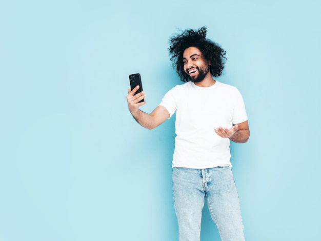 Uomo sorridente bello dei pantaloni a vita bassa che posa nello studio