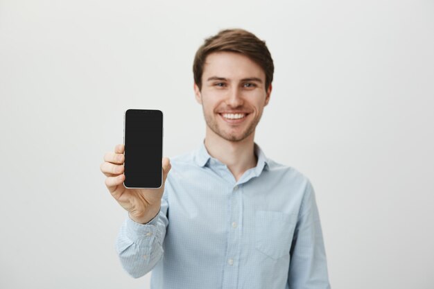 Красивый улыбающийся человек, показывающий экран смартфона