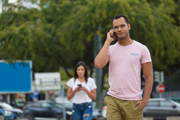 Handsome smiling man talking on phone while walking on street