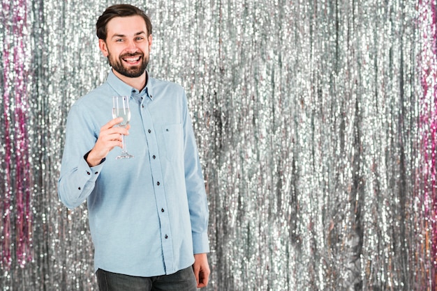 Free photo handsome smiling man with glass near tinsel