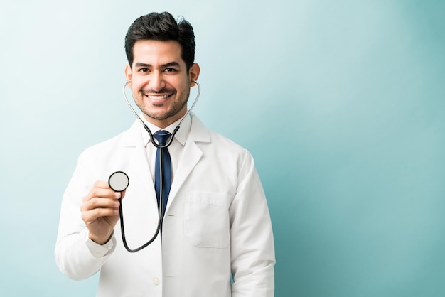 Esame medico sorridente bello con lo stetoscopio sopra fondo colorato
