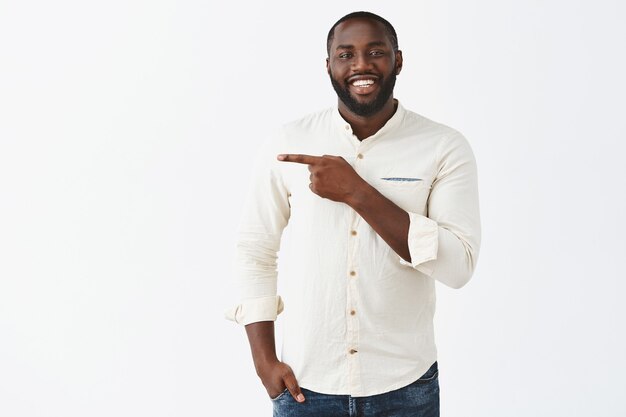 Handsome smiling young guy posing against the white wall