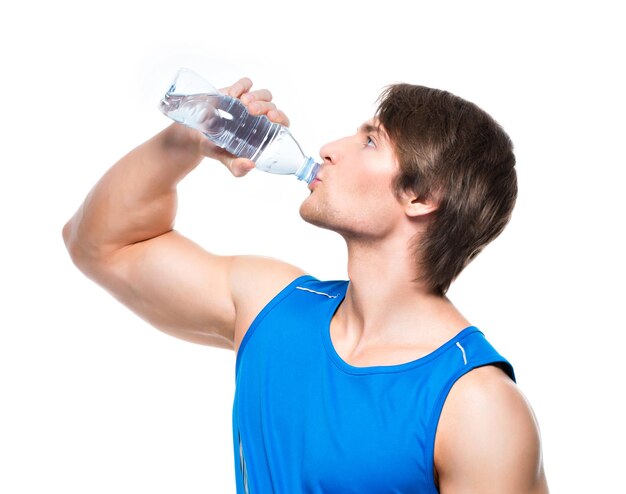 Красивый спортсмен в синей рубашке пьет воду