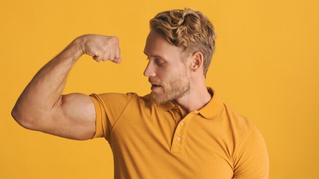 Handsome strong bearded man showing biceps muscles on camera over colorful background Power expression