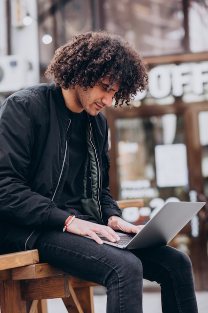 Free photo handsome student with curly hair using laptop