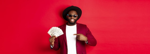 Free photo handsome and stylish african american male model showing money and smiling wearing sunglasses and fa