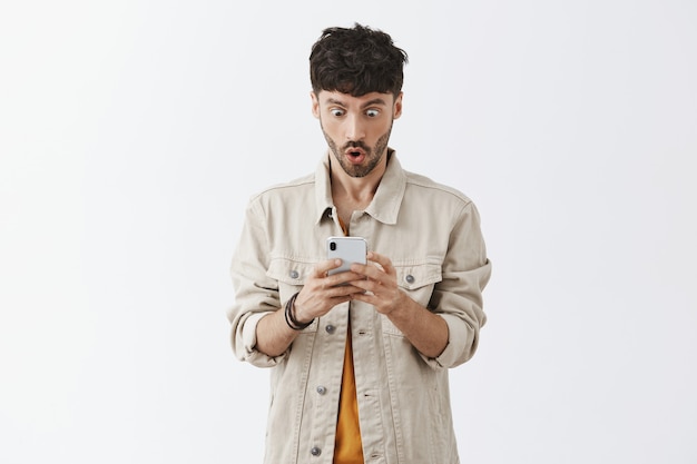 Handsome stylish bearded guy posing against the white wall