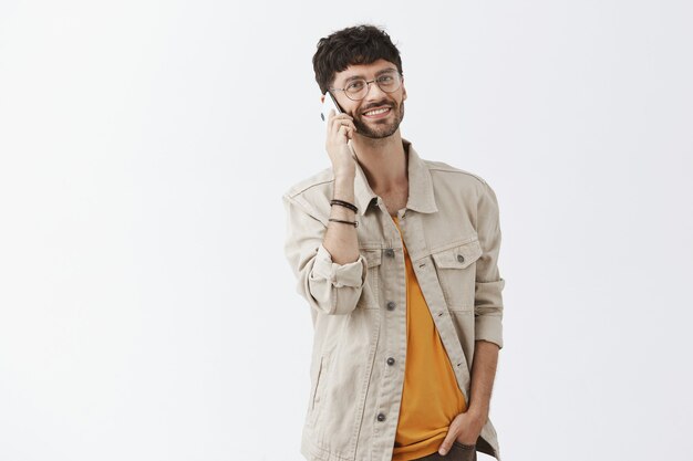 Handsome stylish bearded guy posing against the white wall