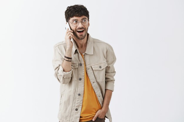 Handsome stylish bearded guy posing against the white wall