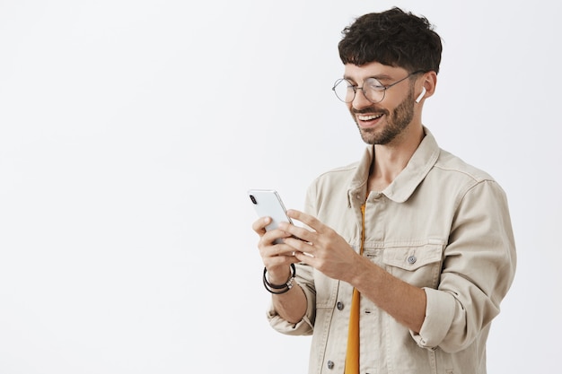 Handsome stylish bearded guy posing against the white wall