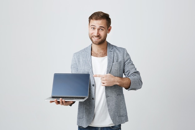 Free photo handsome stylish entrepreneur pointing at laptop display
