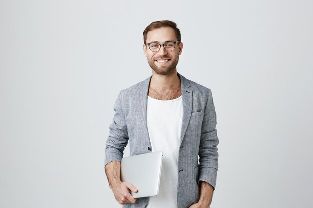 Красивый стильный мужской предприниматель в очках с ноутбуком
