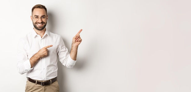 Free photo handsome successful businessman pointing fingers right showing advertisement with pleased face white