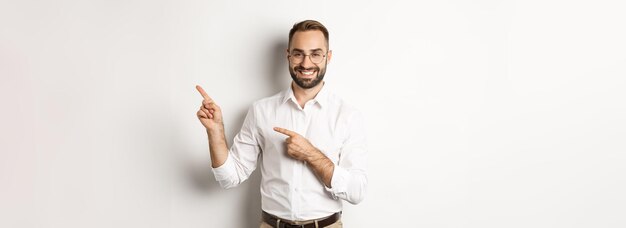 Красивый успешный бизнесмен, указывающий пальцем вправо, показывая рекламу с довольным белым лицом
