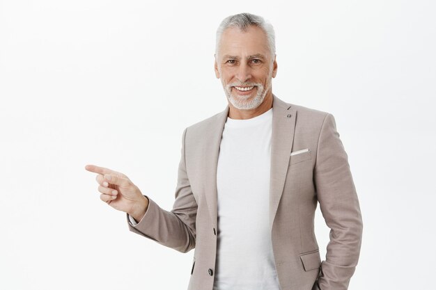 Handsome successful elderly businessman pointing finger left