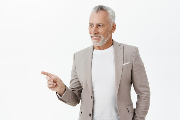 Handsome successful elderly businessman pointing finger left